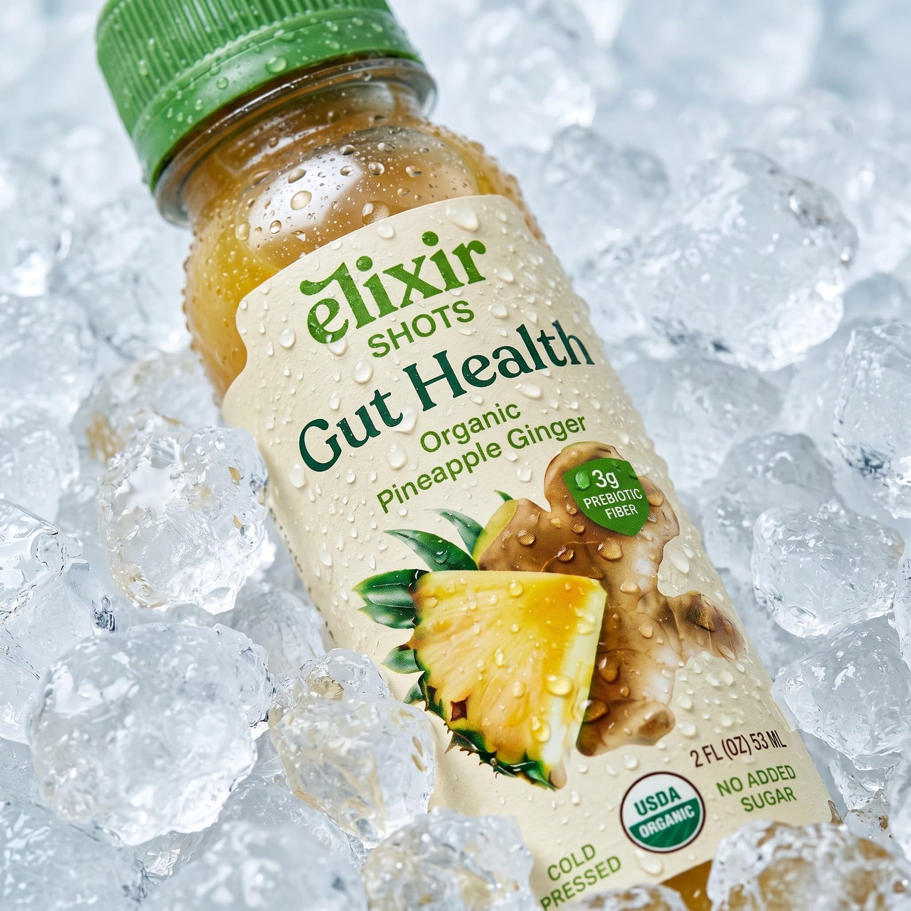 An Elixir Gut Health organic pineapple ginger wellness shot lying on crushed ice